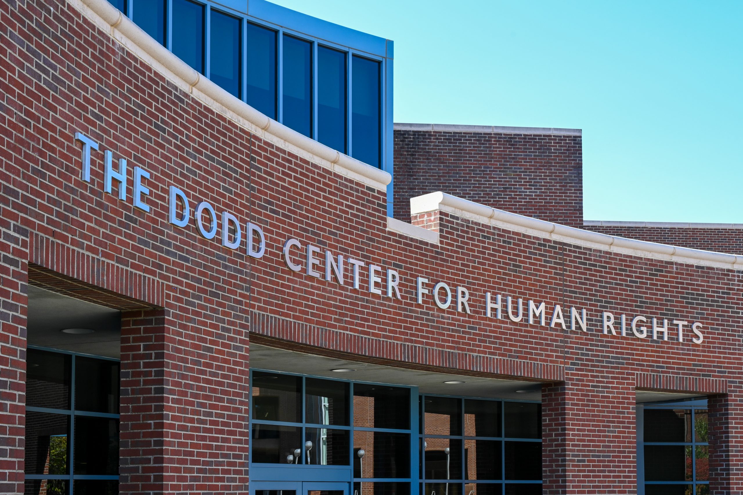 Photo of the exterior of The Dodd Center. Workers attach the letter reflecting the renaming of building as The Dodd Center for Human Rights on Oct. 1, 2021. (Peter Morenus/UConn Photo)