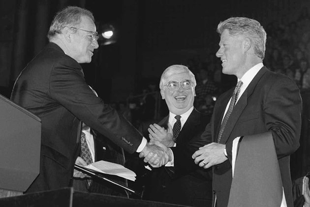 President Bill Clinton receives an honorary degree after his address in Gampel Pavilion on the occasion of the opening of the Thomas J. Dodd Research Center in October 1995. Lewis Rome, left, chairman of the Board of Trustees, presents the degree, as U.S. Sen. Christopher Dodd looks on. (Peter Morenus/UConn Photo)